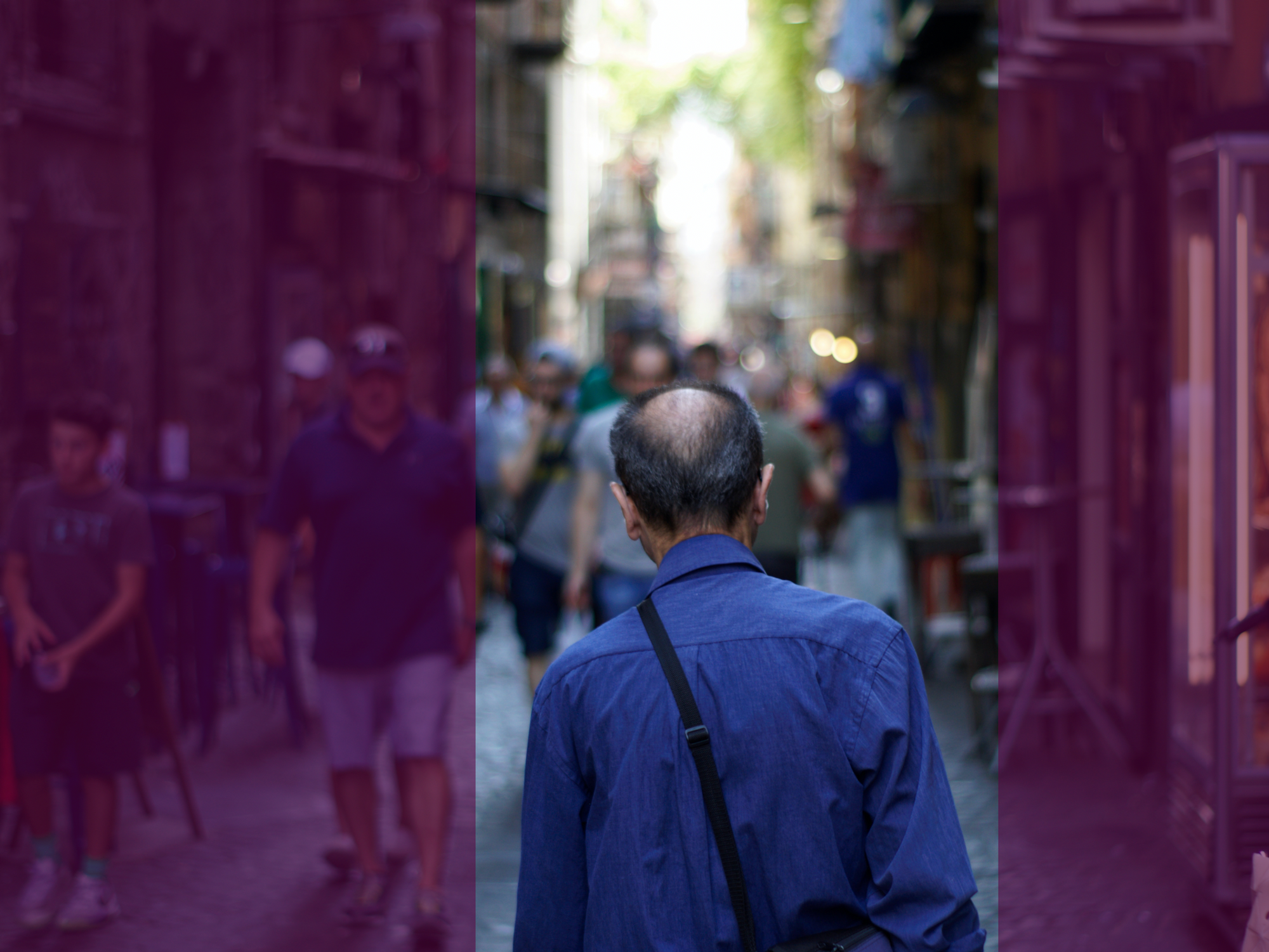 Photograph of a man in a blue shirt walking down a street in Naples