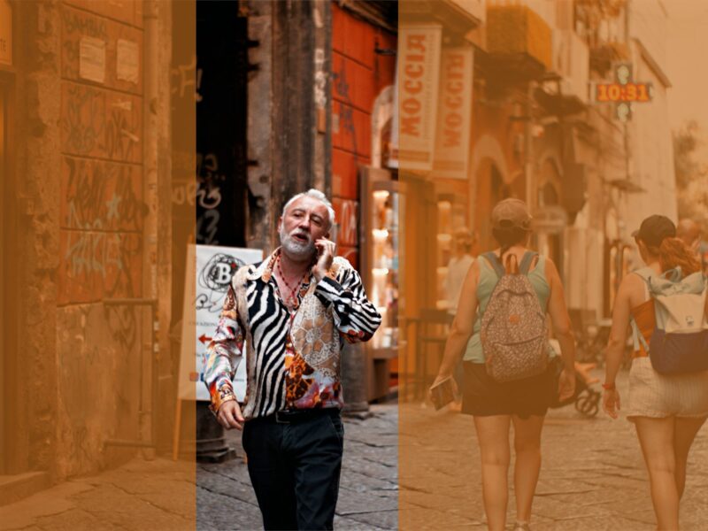 Photograph of a man in a zebra print shirt walking down a Neapolitan street. He is talking on the phone.