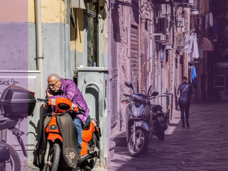 Photograph of a man on a call whilst sitting on his orange motorcycle in the side of a Neapolitan street