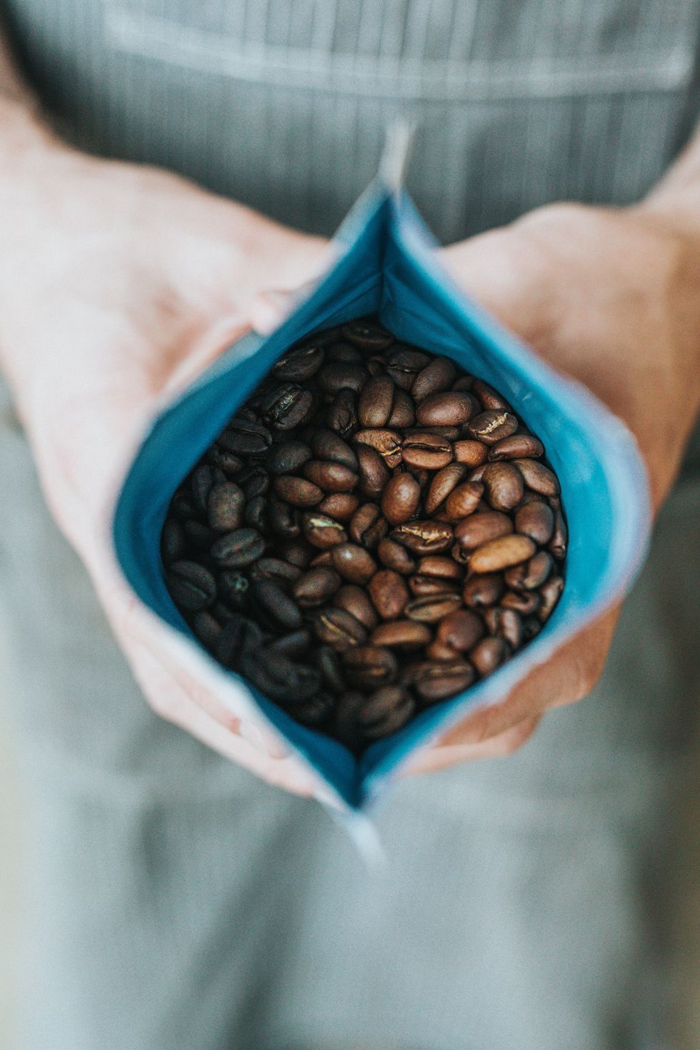 Photograph of a person holding open a pack of coffee beans