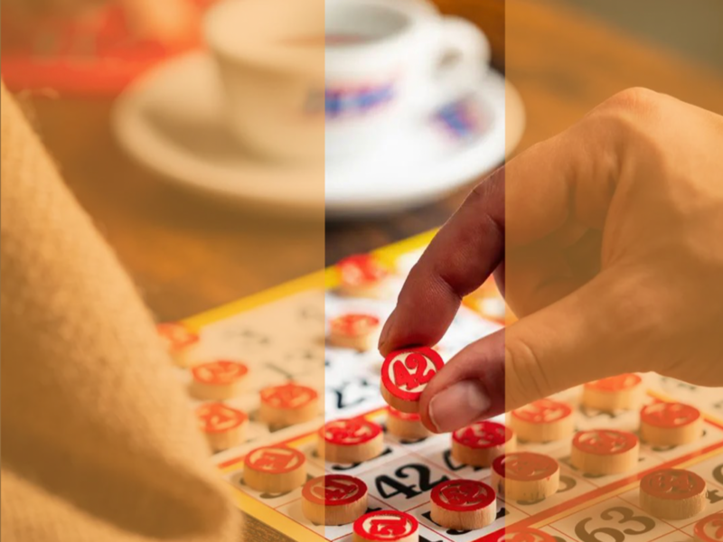 Photograph of a person's hand as they set down a number on a tombola board