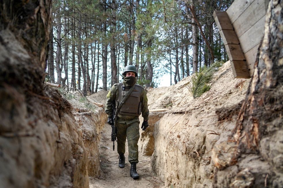 Photograph of a Russian soldier walking inside of a trench on the left bank of the Dnieper​.