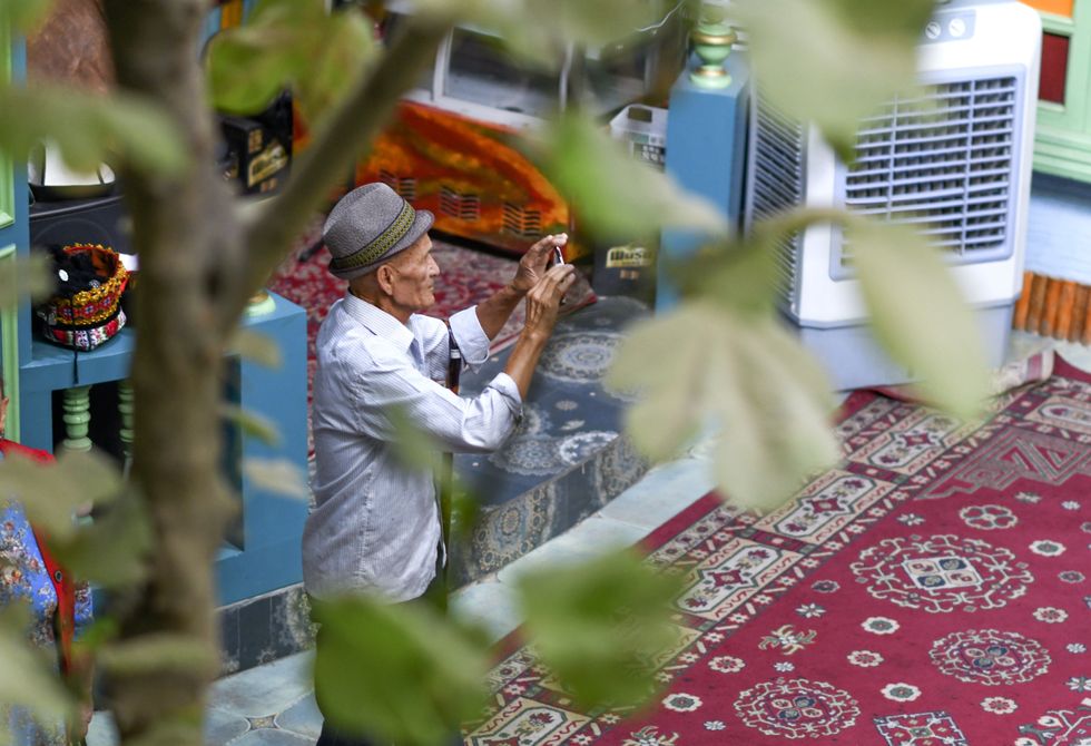 Photograph of a tourist taking photos with his phone at the ancient city of Kashgar scenic area in Kashgar, China.
