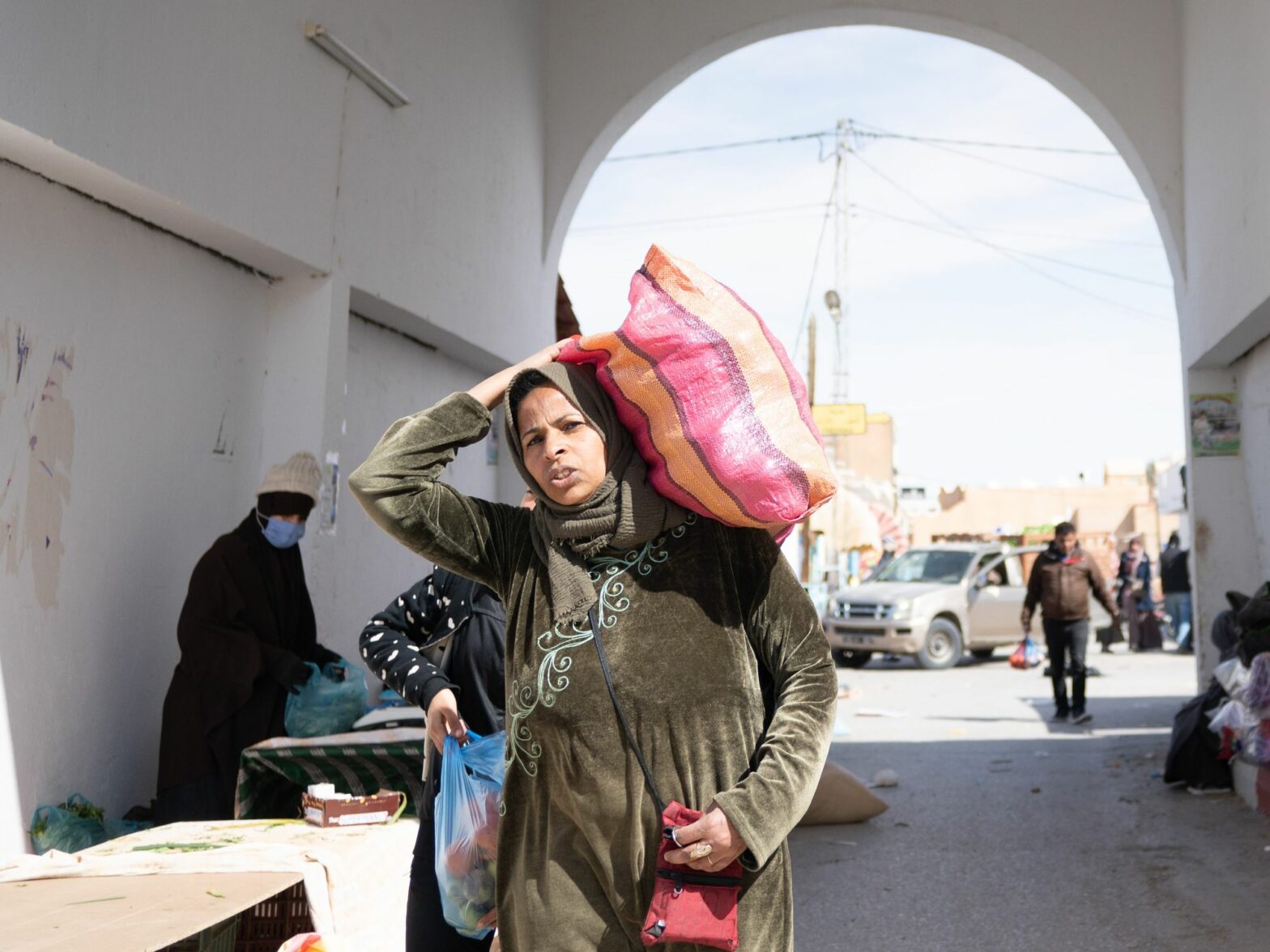 Photograph of a Tunisian woman carrying a bag on her shoulders at the weekly market of Douz