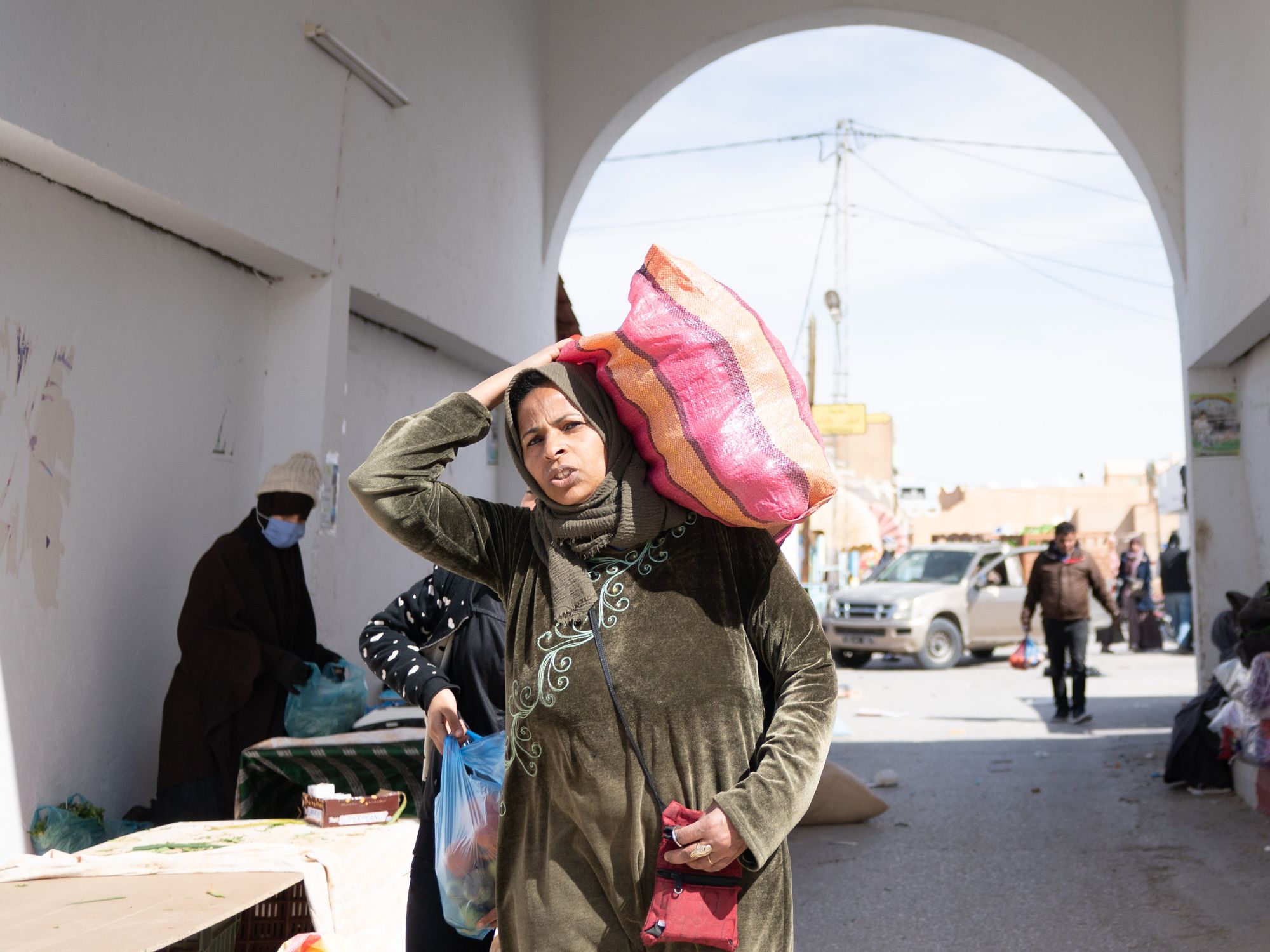 Photograph of a Tunisian woman carrying a bag on her shoulders at the weekly market of Douz