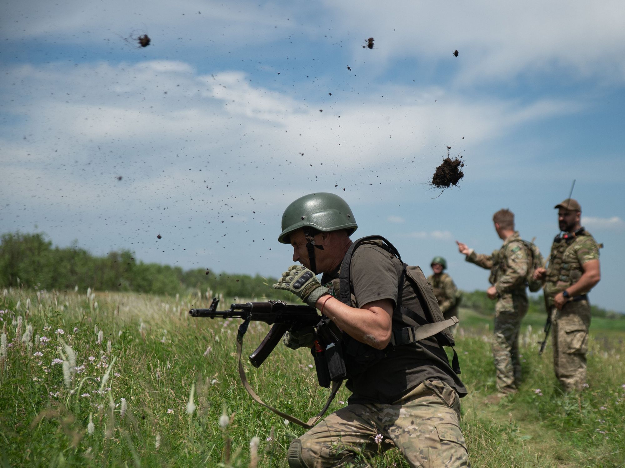 Photograph of a Ukrainian soldier dodging a 'dirt clod grenade' thrown at him by his comrades during training in a field.