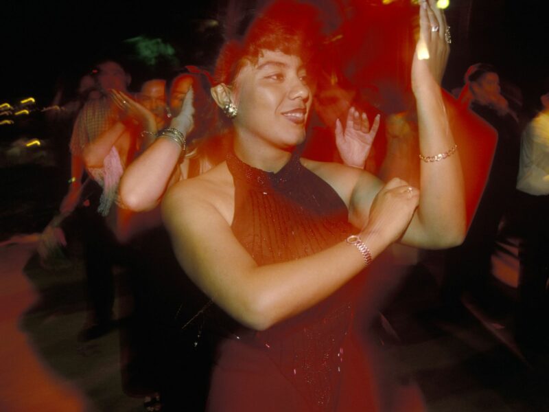Photograph of a woman dancing the Macarena with a group of party-goers in Acapulco, Mexico.