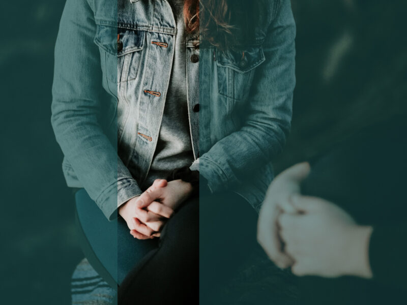 Photograph of a woman's hands clasping one another as she sits.