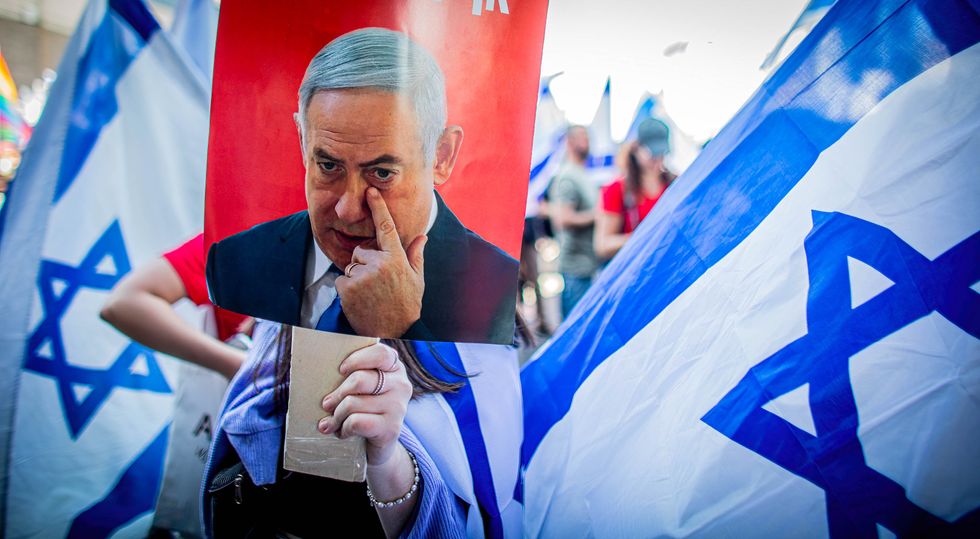 Photograph of an Israeli anti reform protester holding a poster showing Israeli Prime Minister Benjamin Netanyahu during the demonstration.