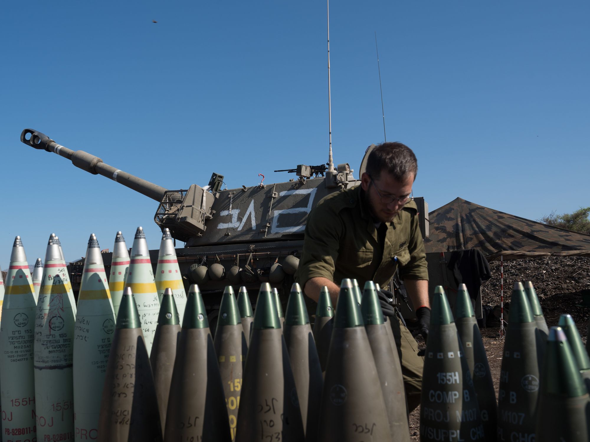 Photograph of an Israeli soldier surrounded by missiles at a position of a self-propelled howitzer deployed in northern Israel bordering Lebanon​