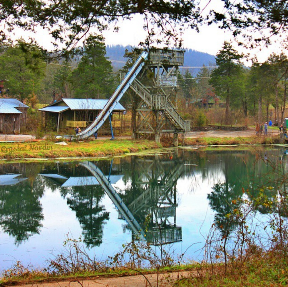 Photograph of an old slide standing in front of a lake in the Dogpatch USA park.