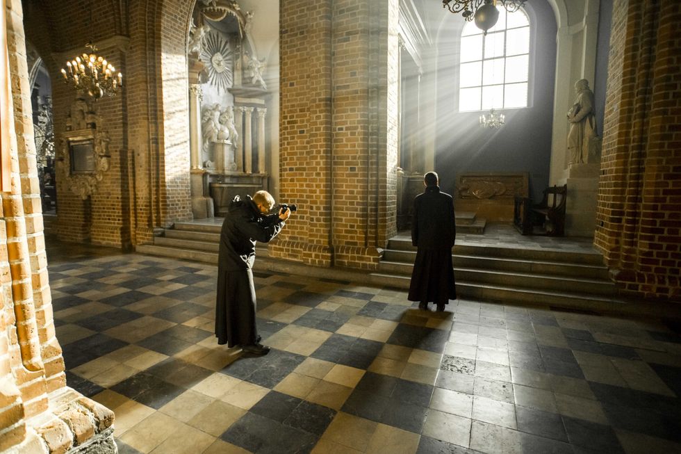 Photograph of Archbishop Stanislaw Gadecki in his church, as a man takes a photograph of him.