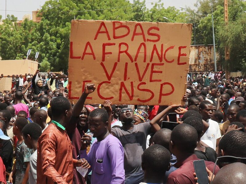 Photograph of demonstrators in Niger taking part in a march in support of the coup plotters in the capital, centered by a sign reading ''Down with France, long live the CNSP''​
