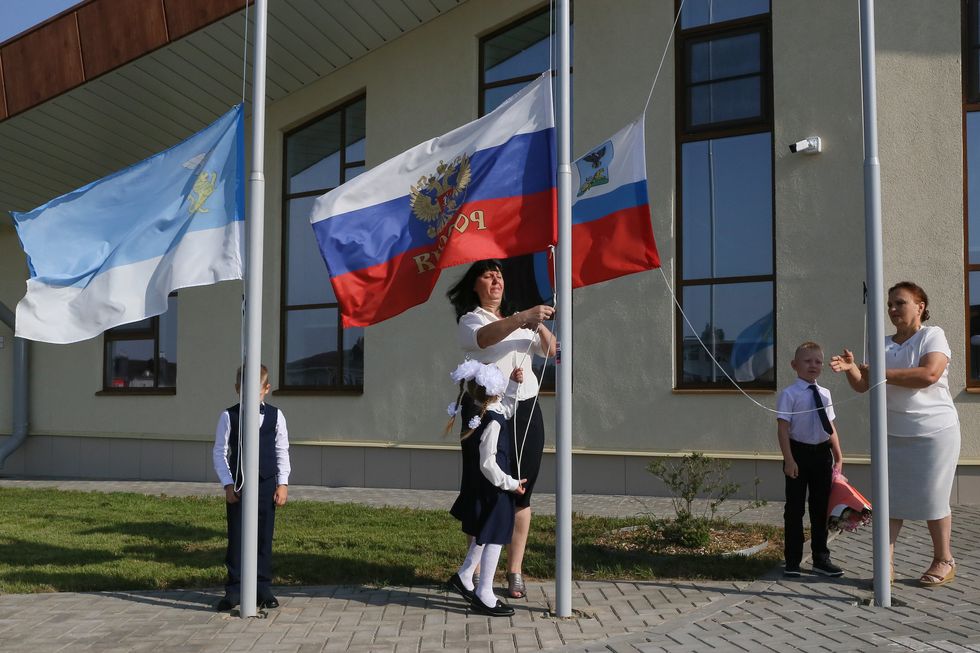 Photograph of ​women raising Russian flags on Knowledge Day as a new academic year starts at primary / nursery school