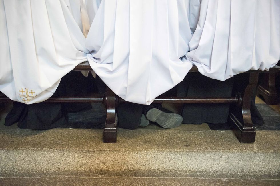 Photograph of feet kneeling at a solemn holy mass held during the 30th anniversary of the episcopal ordination of Poznan by Archbishop Stanislaw Gadecki.
