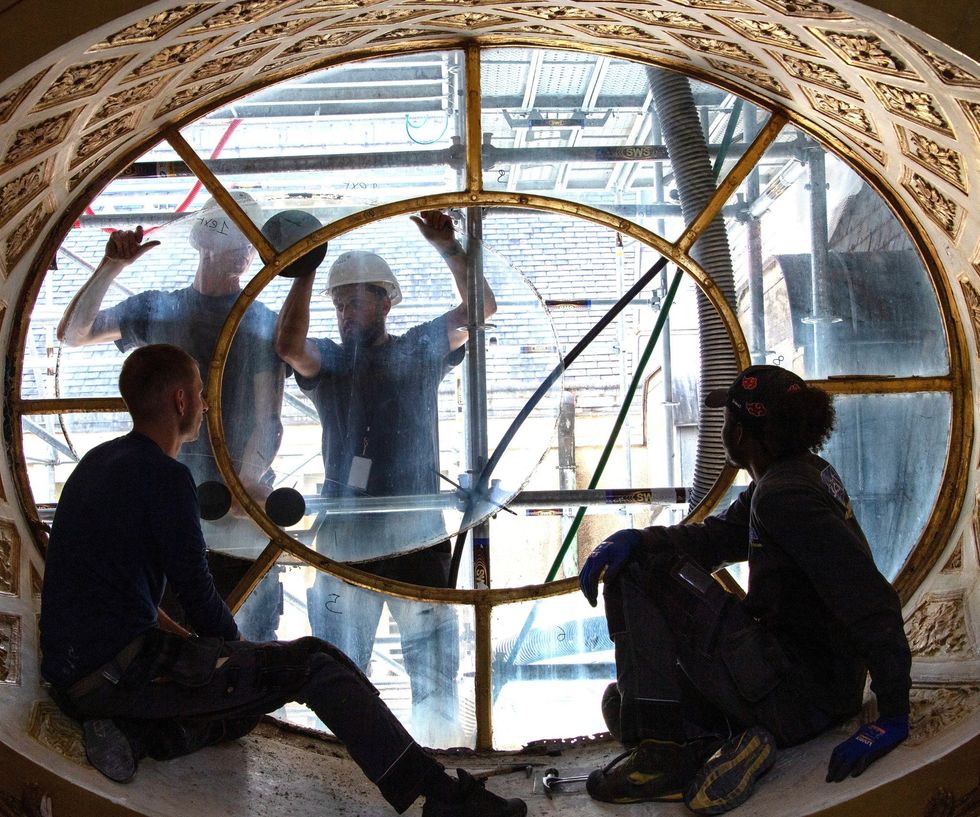 Photograph of four workers fixing a windows at the Palace of Versailles