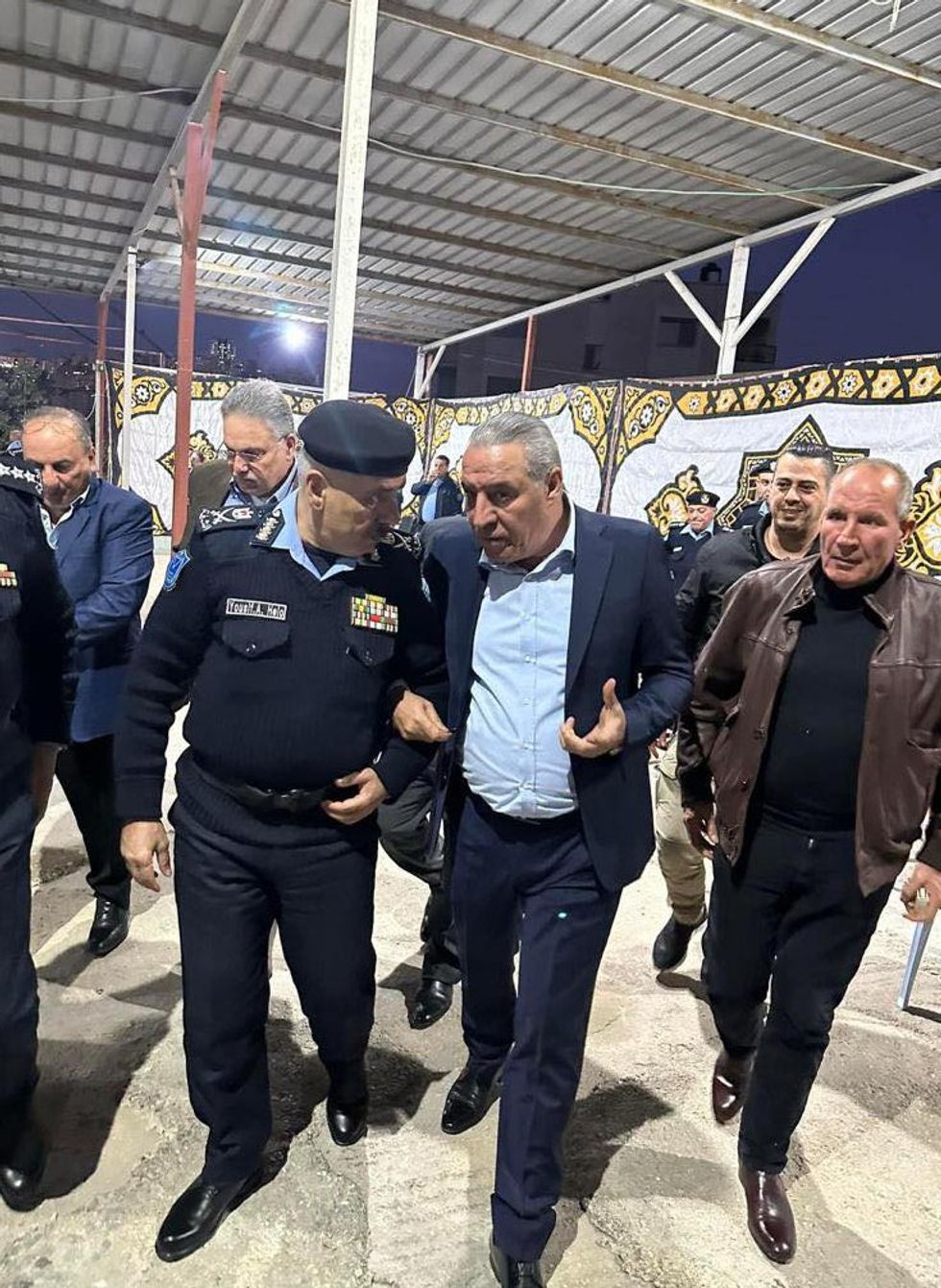Photograph of Hussein Al-Sheikh talking to Palestinian police arm in arm.