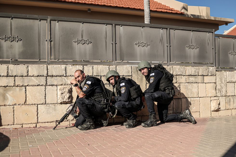 Photograph of Israeli police officers taking cover behind a wall during a rocket attack from Gaza.