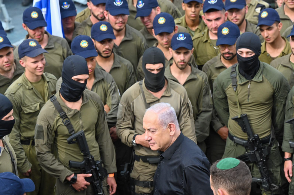 Photograph of Israeli Prime Minister Bejjamin Netanyahu surrounded by IDF soldiers as he visits troops.