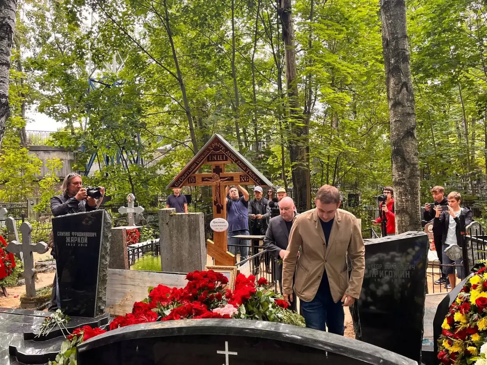 Photograph of men standing around Prigozhin's grave in the Porokhovskoye cemetery.