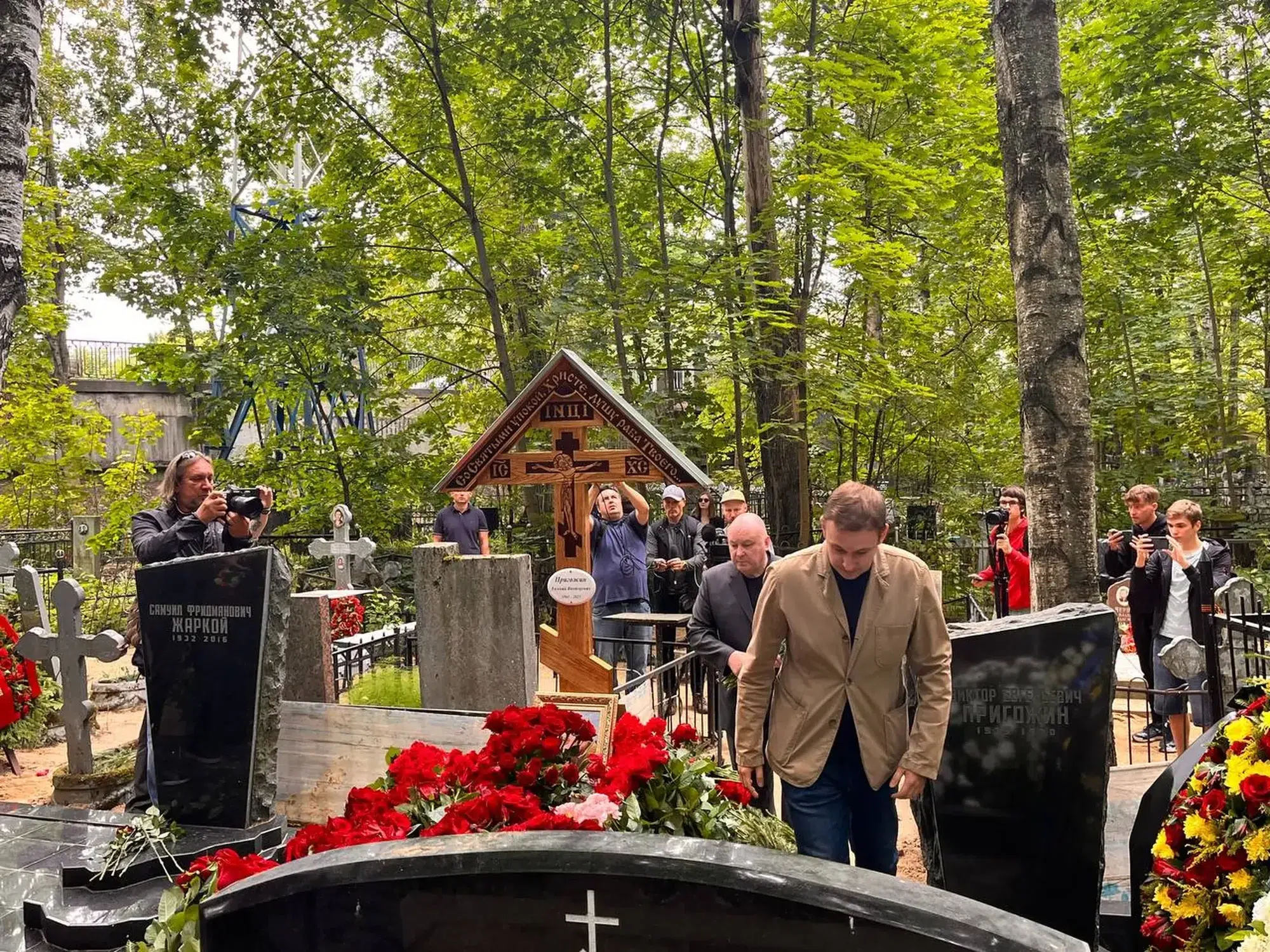 Photograph of men standing around Prigozhin's grave in the Porokhovskoye cemetery.