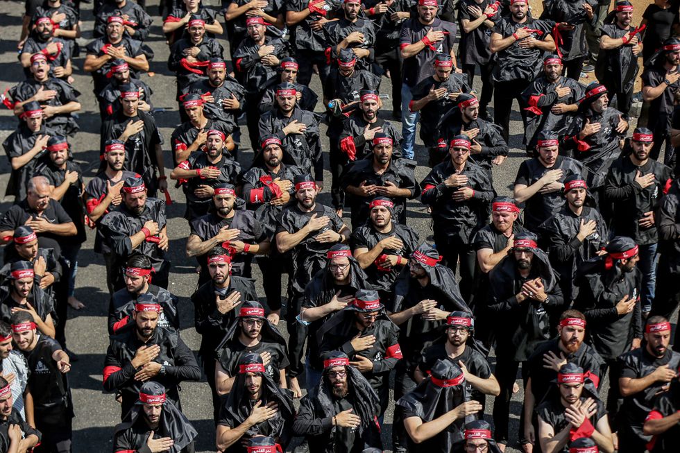 Photograph of militants of Hezbollah standing in lines as they perform a parade during a mass rally.