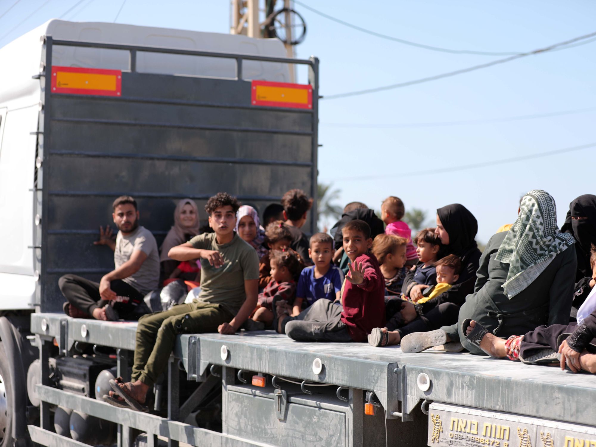 Photograph of Palestinian women, children and men sitting on a truck as they flee Gaza City.