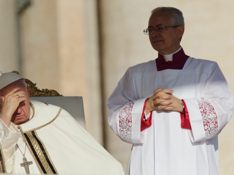 Photograph of Pope Francis holding his hand against his forehead.