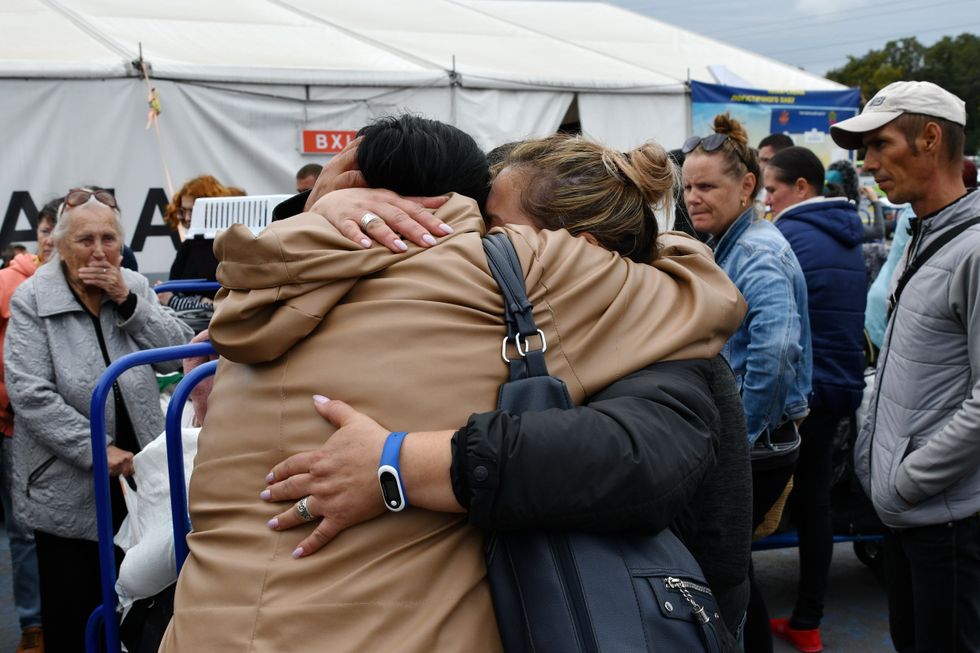 Photograph of refugees hugging during the evacuation of civilians at a refugee centre in Zaporizhzhia.