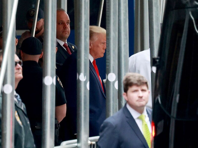 Photograph of stone-faced former President Donald Trump walks out of the Manhattan District Attorney Offices.