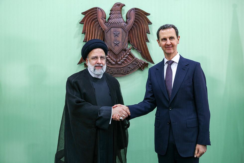Photograph of Syria's President Bashar Al-Assad shaking hands with his Iranian counterpart Ebrahim Raisi