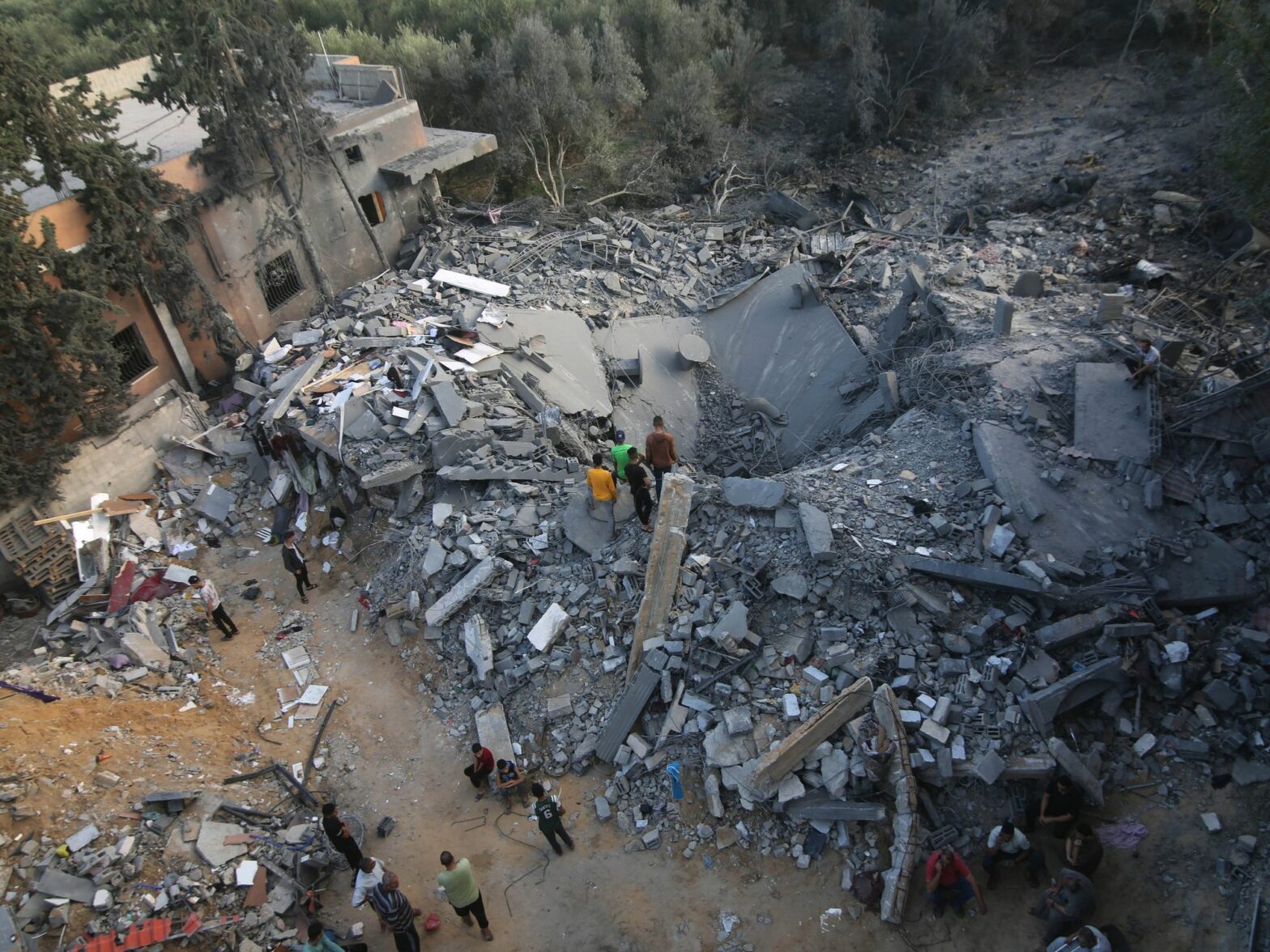 Photograph of the rubble of buildings destroyed by Israeli airstrikes in the southern Gaza Strip city​. People lean in to look at the destruction.