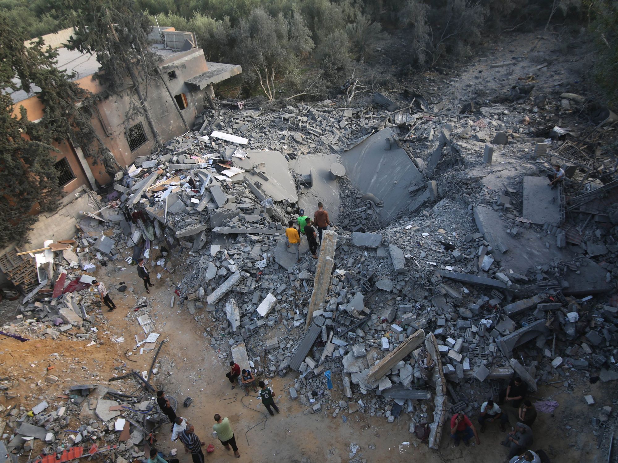 Photograph of the rubble of buildings destroyed by Israeli airstrikes in the southern Gaza Strip city​. People lean in to look at the destruction.
