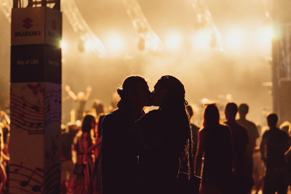 Photograph of the silhouette of a man and a woman kissing during a concert