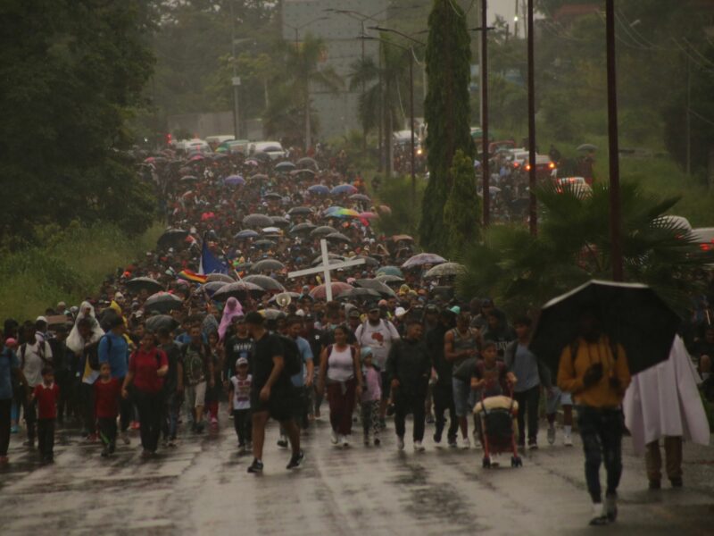 Photograph of thousands of migrants marching to the US-Mexican border under the rain.
