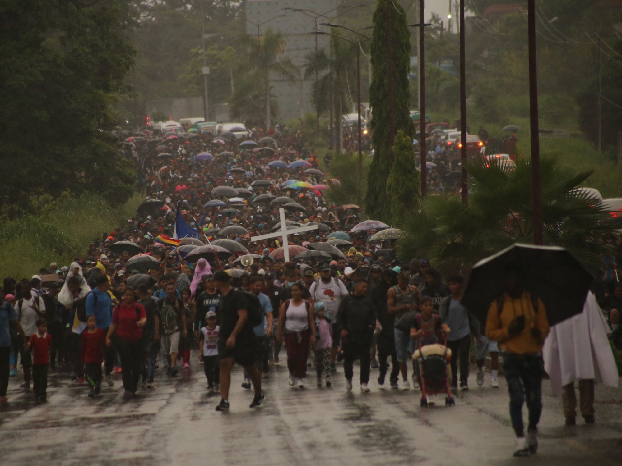Photograph of thousands of migrants marching to the US-Mexican border under the rain.