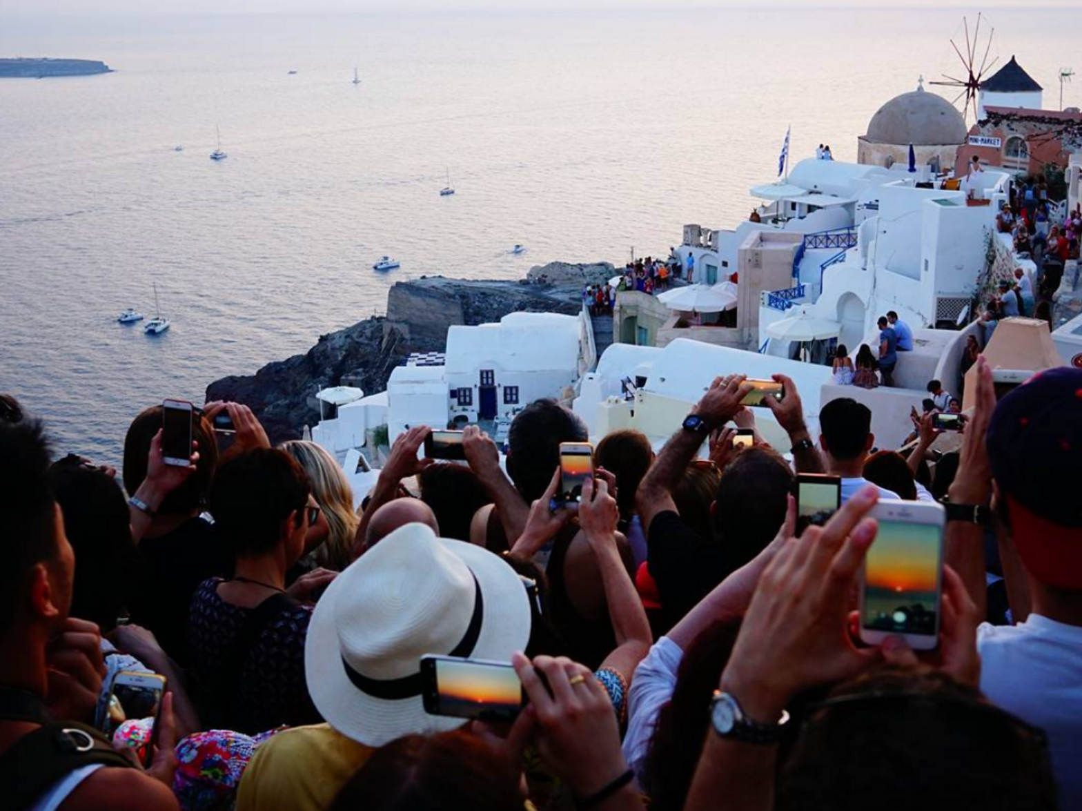 Photograph of tourist crowding on a cliff to take a photo of the sunset in Santorini