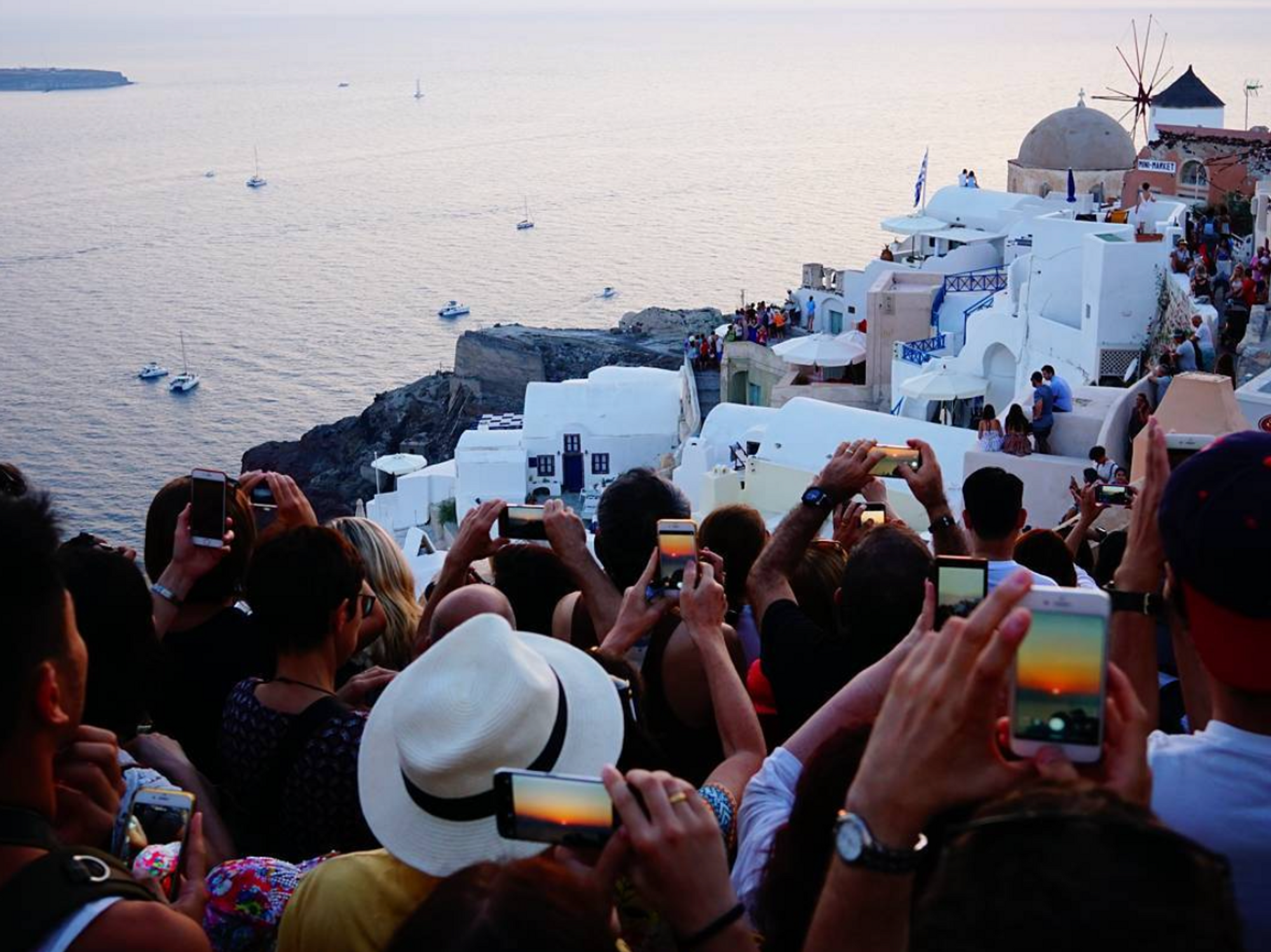 Photograph of tourist crowding on a cliff to take a photo of the sunset in Santorini