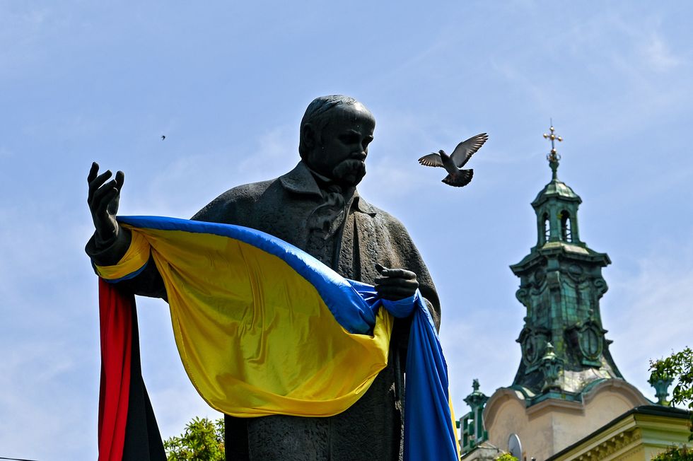 Pigeon flying past statue of Taras Shevchenko