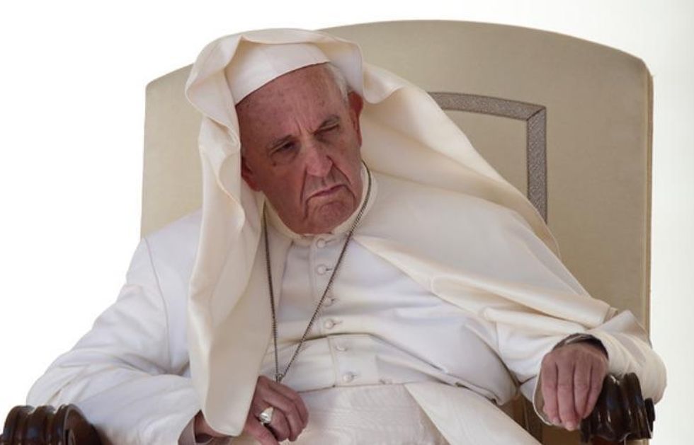 Pope Francis, sitting on a chair and looking upset.