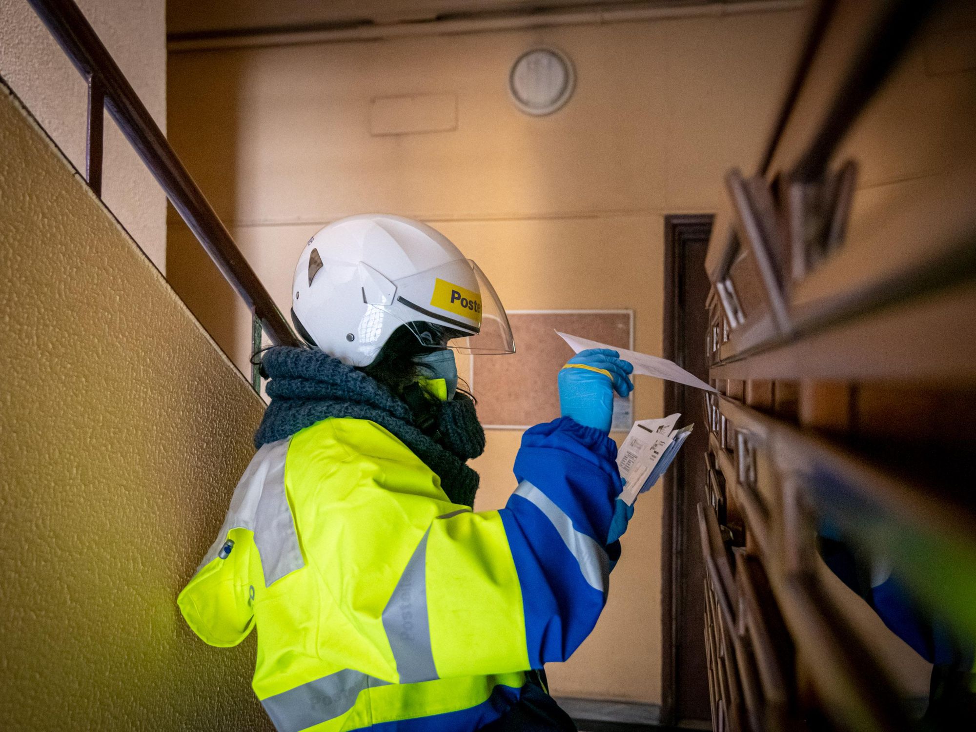 Postal worker in Italy delivers mail to apartment mailboxes