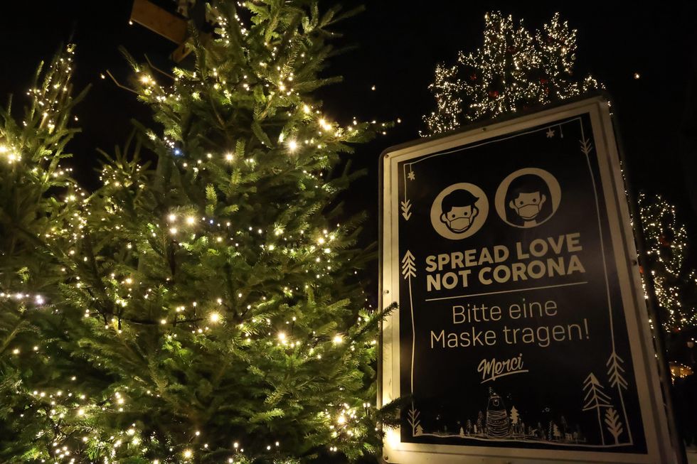 poster with mask wearing warning sign at a Christmas market with illuminated hristmas trees