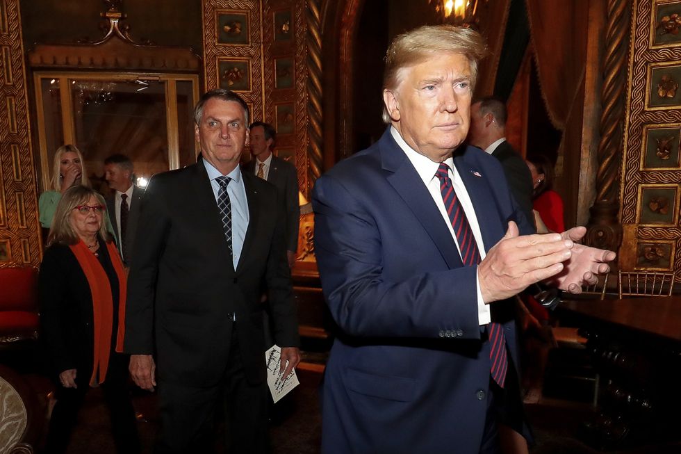 President Donald Trump escorts Brazilian President Jair Bolsonaro to a dinner.