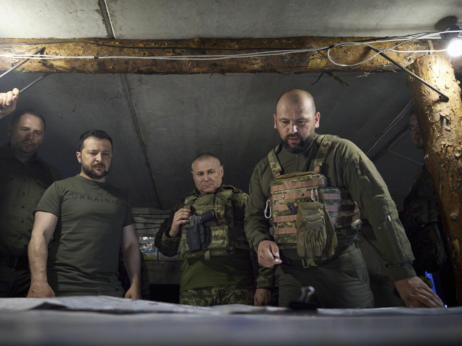 President Volodymyr Zelensky looks down a map with three other Ukrainian servicemen