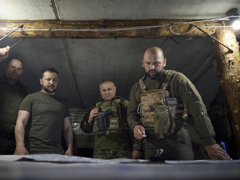 President Volodymyr Zelensky looks down a map with three other Ukrainian servicemen
