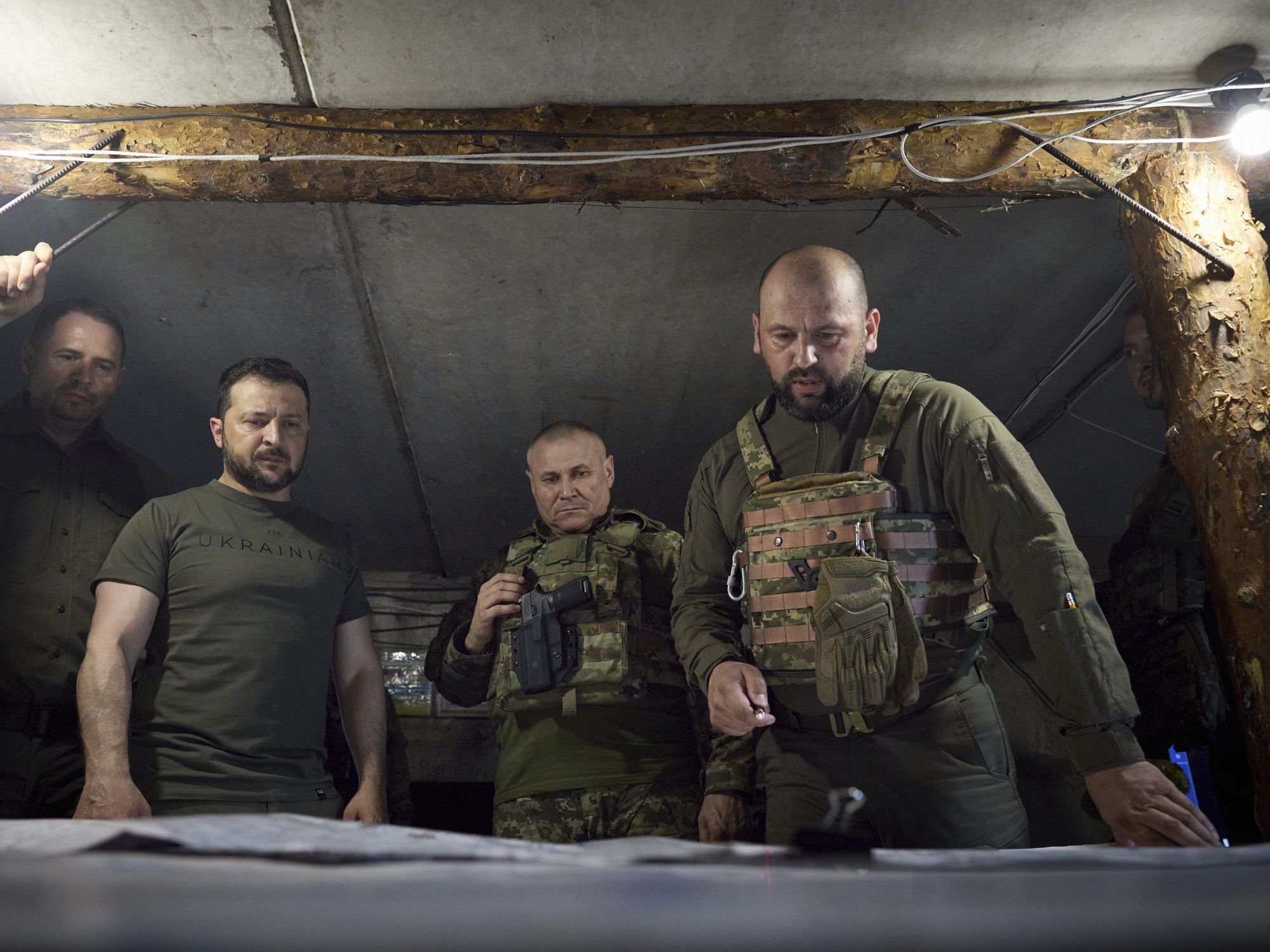 President Volodymyr Zelensky looks down a map with three other Ukrainian servicemen