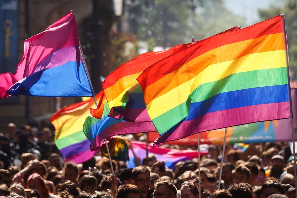 Pride flags and a bisexual flag are held aloft over a crowd of people in Poland