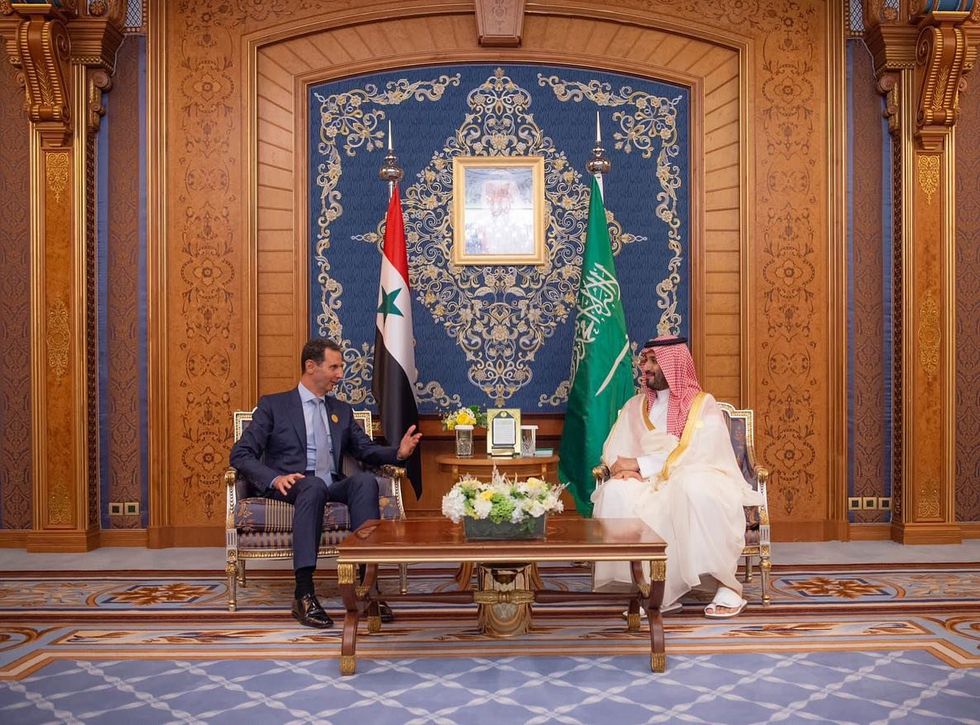 Prince Mohammed bin Salman sits facing Syrian President Bashar in front of their national flags.