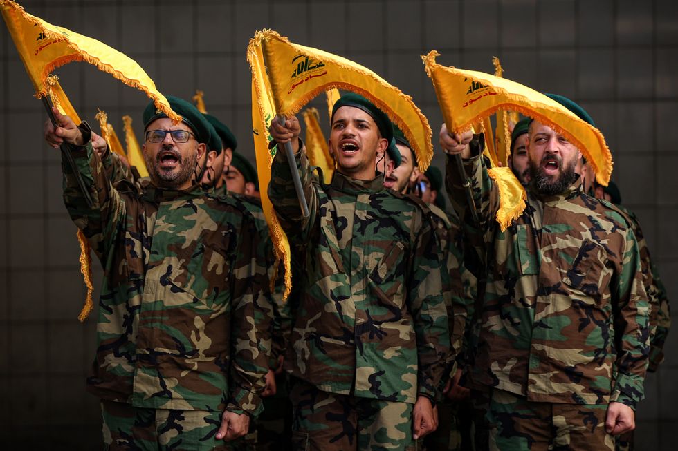 Pro-Iranian Hezbollah militants chant slogans during the funeral procession of a militant killed in clashes against Israeli forces.