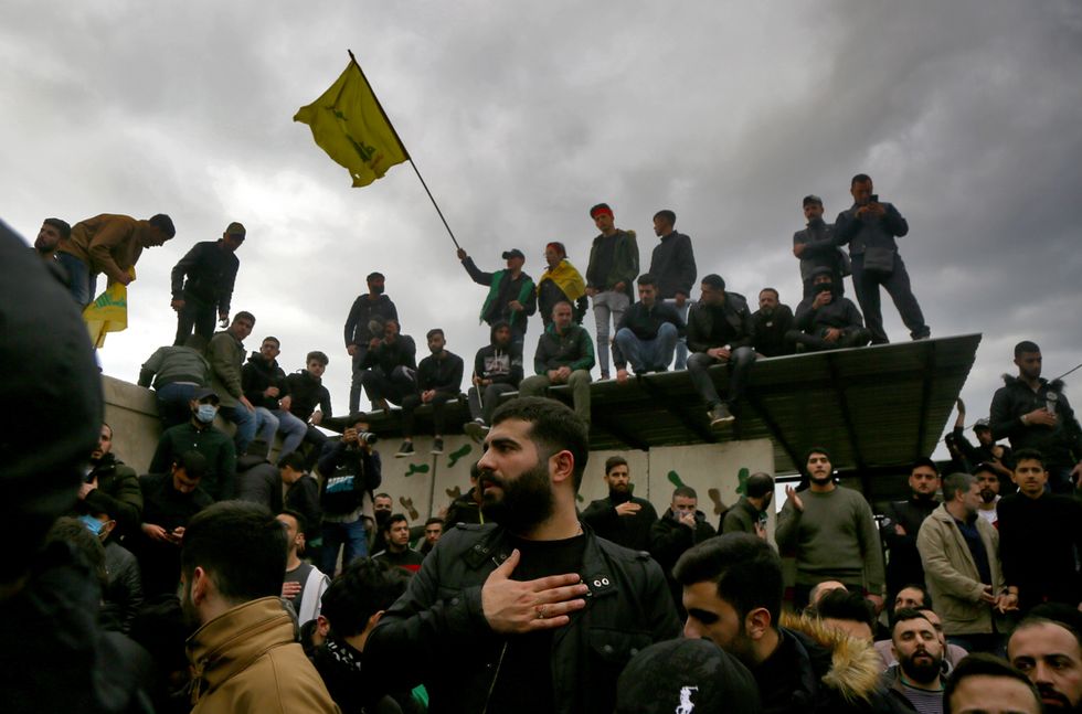 Pro-Iranian Hezbollah militants hold flags and shout slogans during the funeral procession of five of their colleagues.